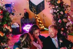 Emily-and-Mark-seated-with-guest-and-DJ-in-background